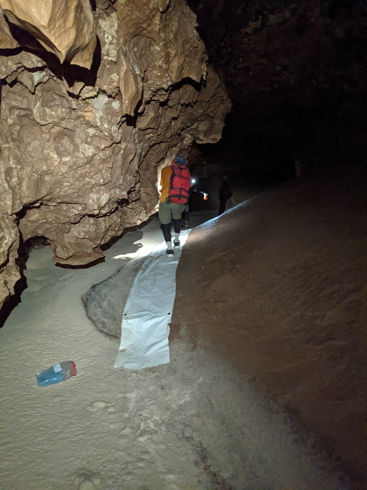 Ramon walking on a tarp next to Snowy, awkwardly avoiding a dirty protrusion in the passage wall right next to the tarp Ramon walking on a tarp next to Snowy, awkwardly avoiding a dirty protrusion in the passage wall right next to the tarp