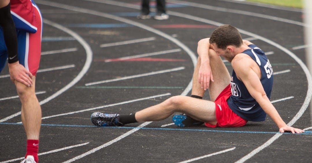 a man sitting on the ground in a track a man sitting on the ground in a track