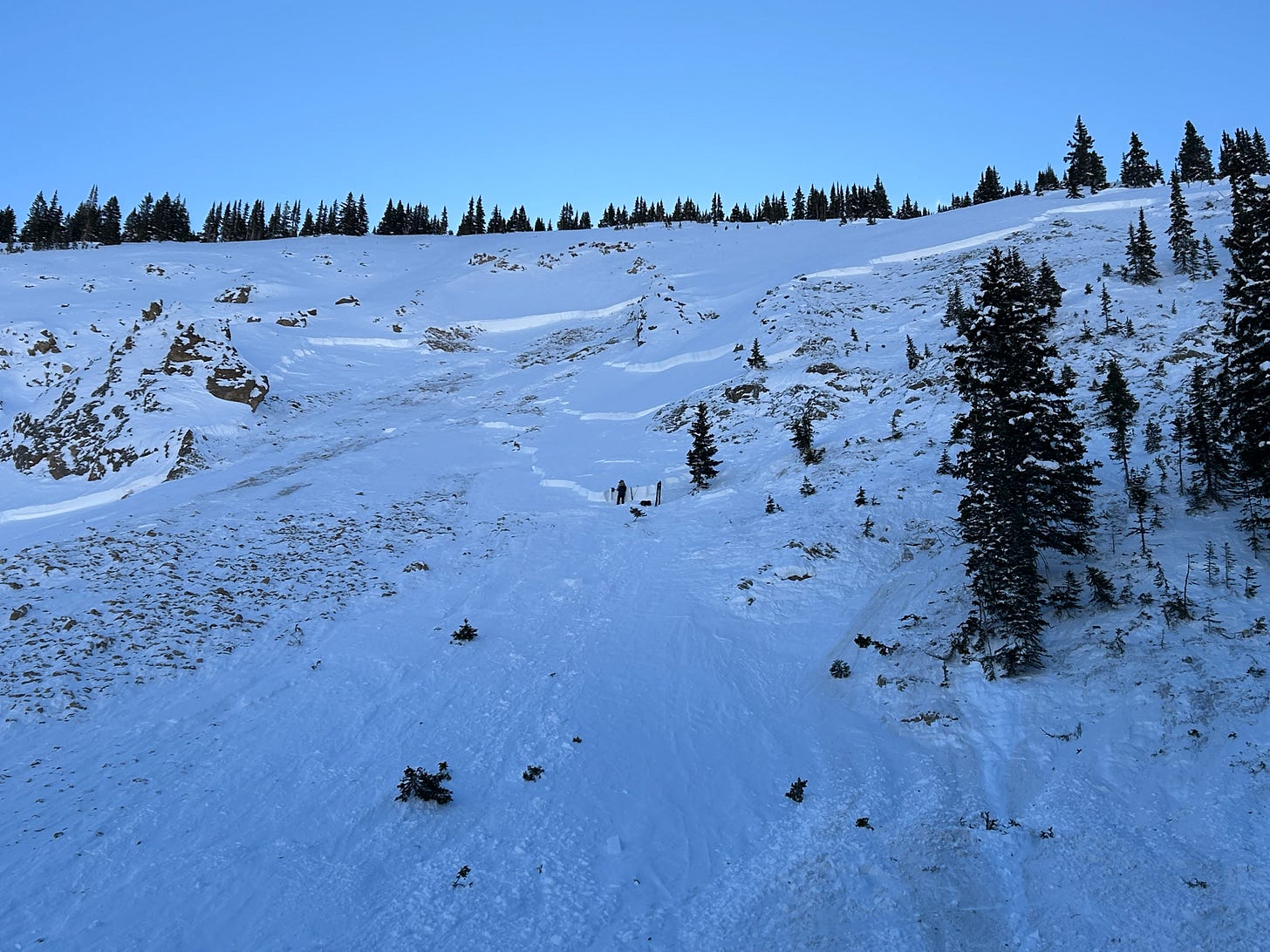 Looking up at the avalanche in High Trail Cliffs. A CAIC forecaster is observing a snow profile at the lower portion of the crown face.