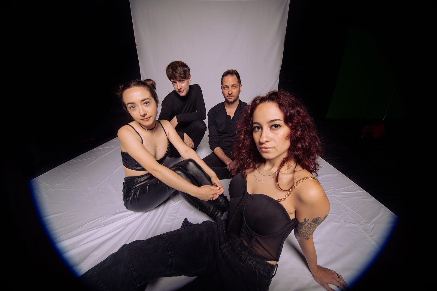 A photo of the members of Flowerbomb reclining on the floor of a photo studio with a plain white backdrop.. A photo of the members of Flowerbomb reclining on the floor of a photo studio with a plain white backdrop..
