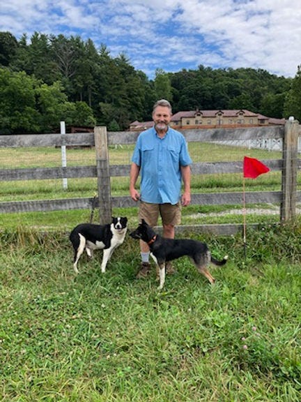 Standing in front of the barn at Biltmore Estate, man with his two sheep herding dogs