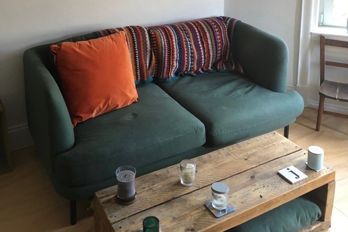 unlit candles on wooden coffee table in front of couch with pillow and a blanket on it unlit candles on wooden coffee table in front of couch with pillow and a blanket on it