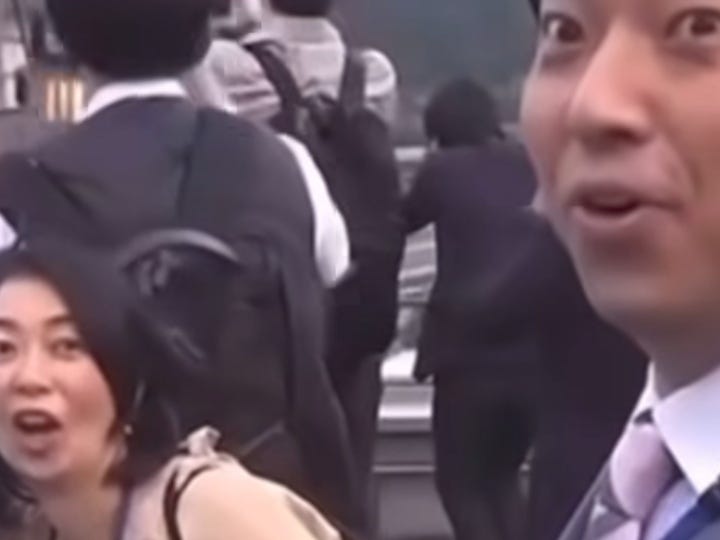 O print mostra 3 pessoas de costas e duas pessoas em primeiro plano - uma mulher à esquerda e um homem à direita, ambos com uma expressão impressionada.