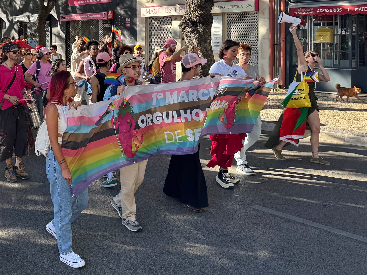 Marchers carry a banner reading “1st LGBTQIA+ Pride March in Setúbal.”