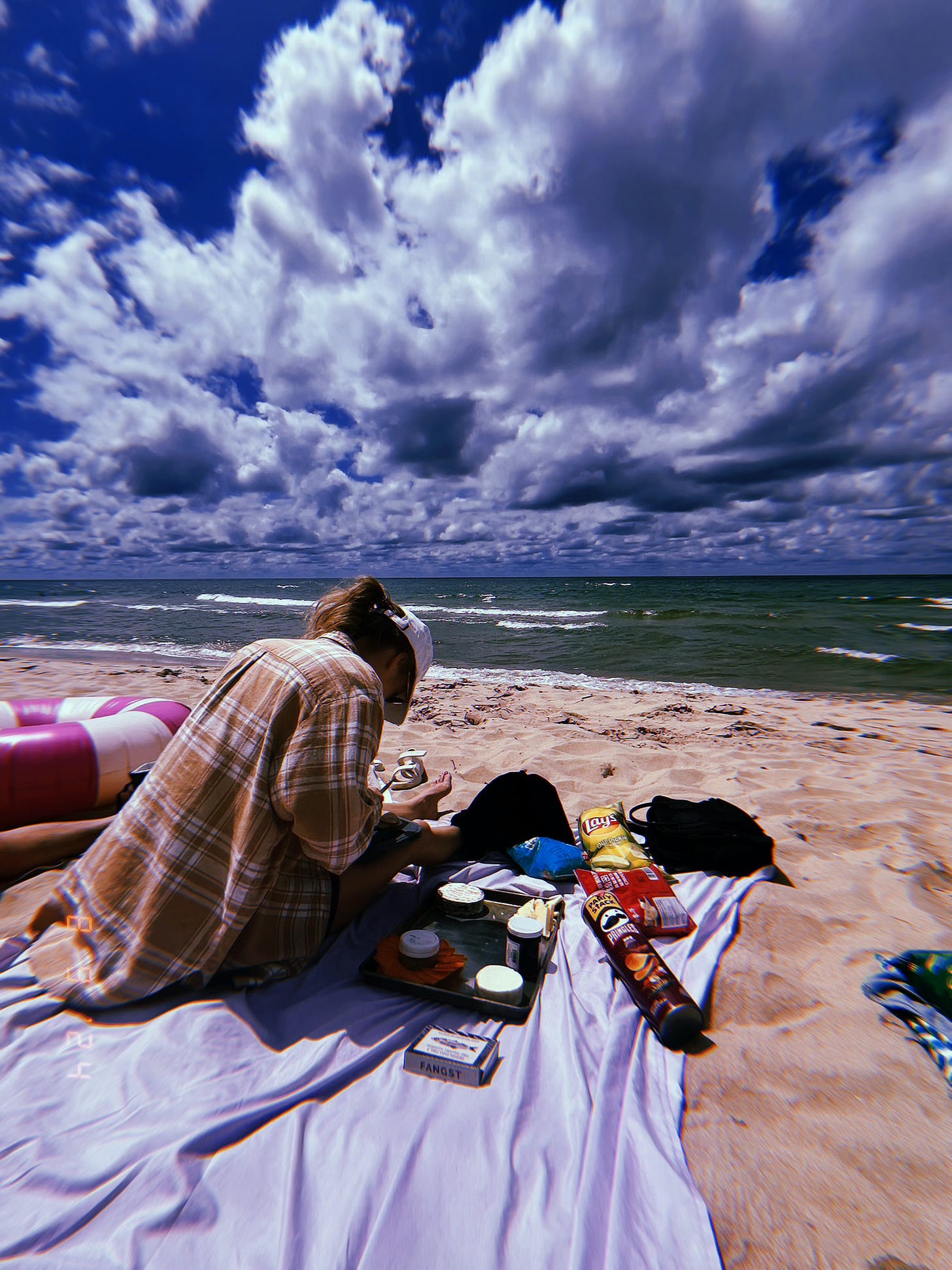 Erika builds a cheese plate on the beach with Lake Michigan in the background