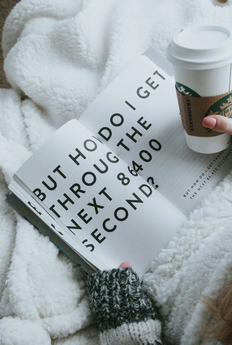 woman sitting on bed while holding Starbucks cup