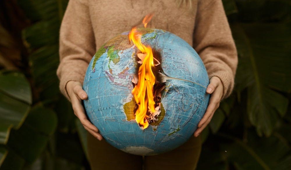 Free A symbolic portrayal of climate change with a burning globe held in hands, set against a nature background. Stock Photo