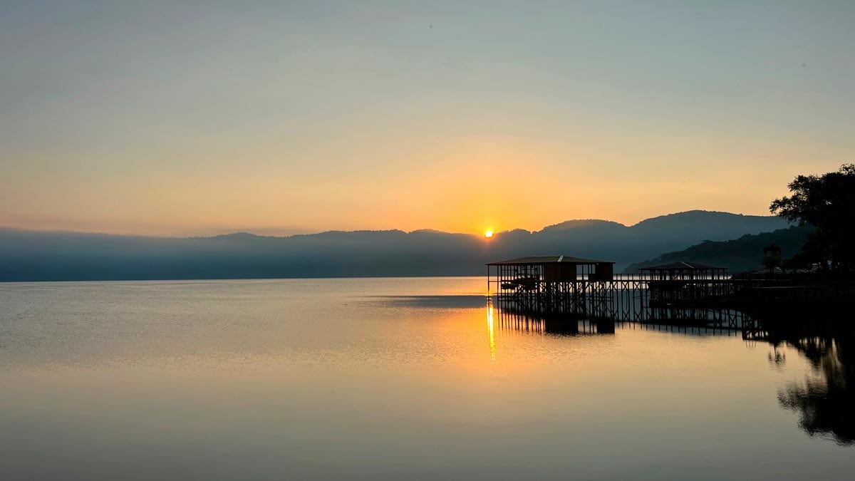 dock reflected in lake at sunrise