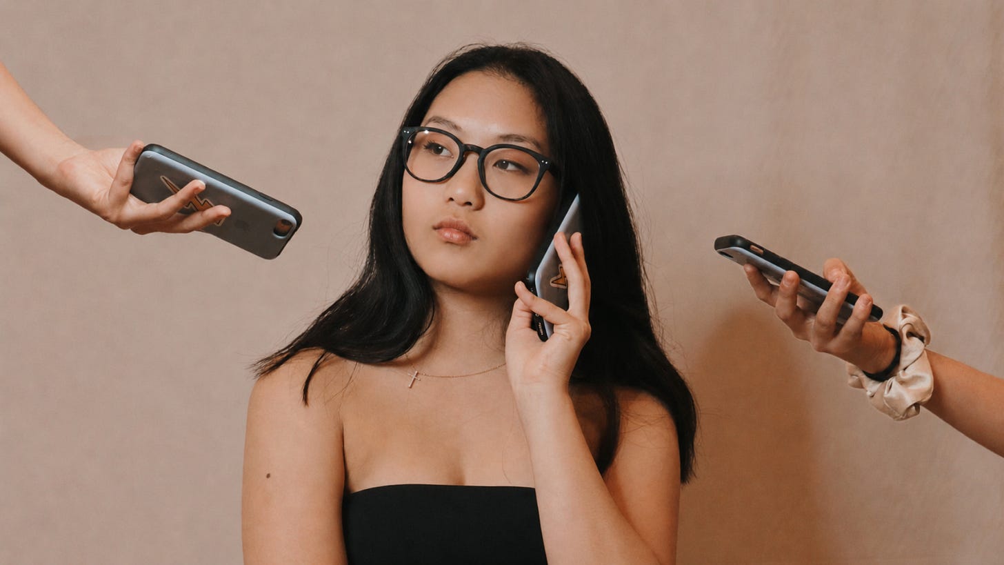 asian female listening on her phone while others are pointing their cell phones at her. asian female listening on her phone while others are pointing their cell phones at her.