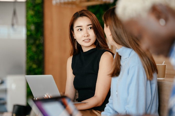 Two women are talking with a laptop in front of one person. One women is interviewing the other. Two women are talking with a laptop in front of one person. One women is interviewing the other.