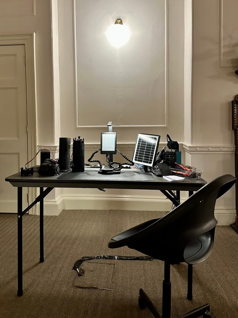 A cluster of devices, batteries, and portable screens with messy wires which are all part of an installation called The Horizon by the artist-researcher Wesley Goatley. A cluster of devices, batteries, and portable screens with messy wires which are all part of an installation called The Horizon by the artist-researcher Wesley Goatley.