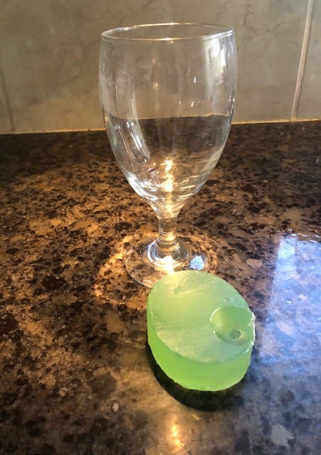 A glass with a green soap bar on a counter

Description automatically generated