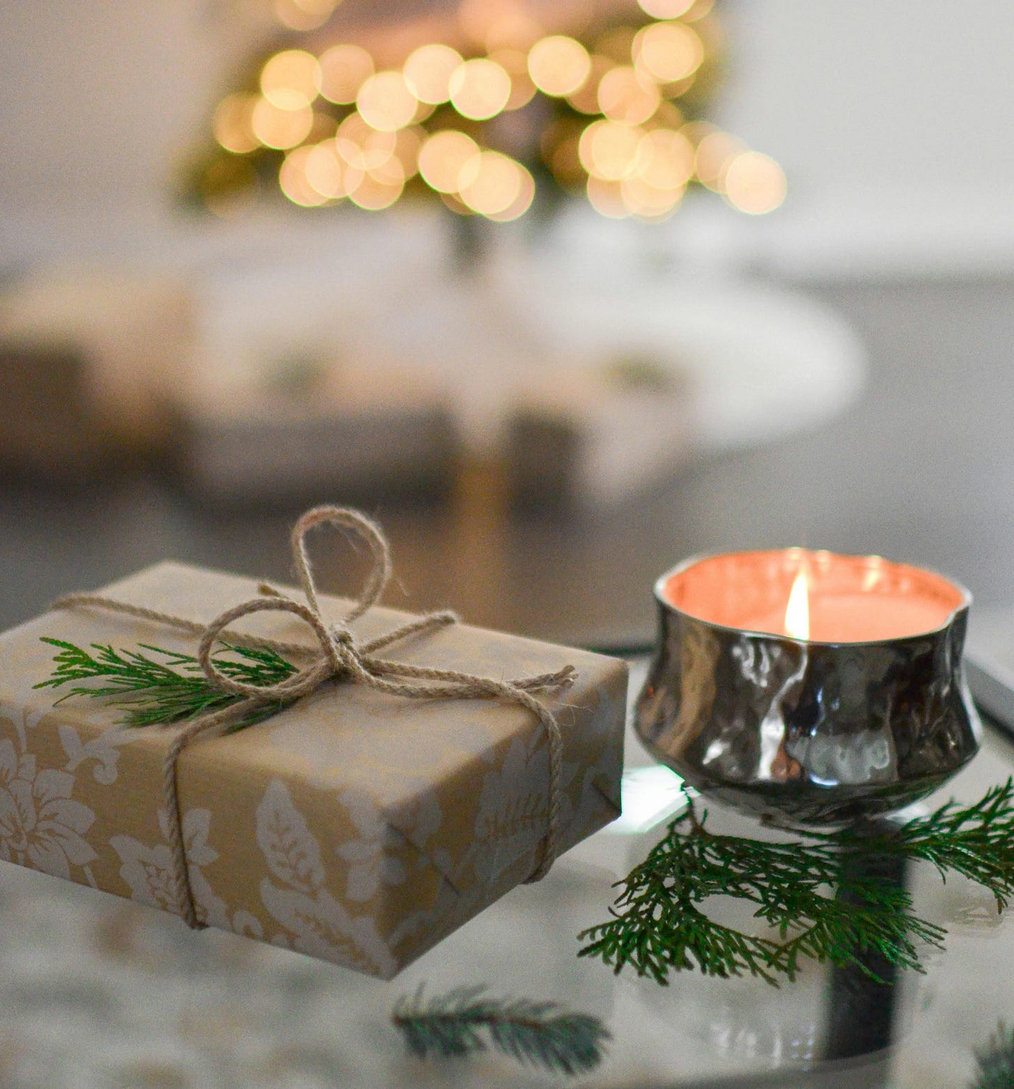 “A small wrapped gift and lit candle with a softly glowing Christmas tree in the background, symbolizing simple, Christ-centered Christmas joy.”