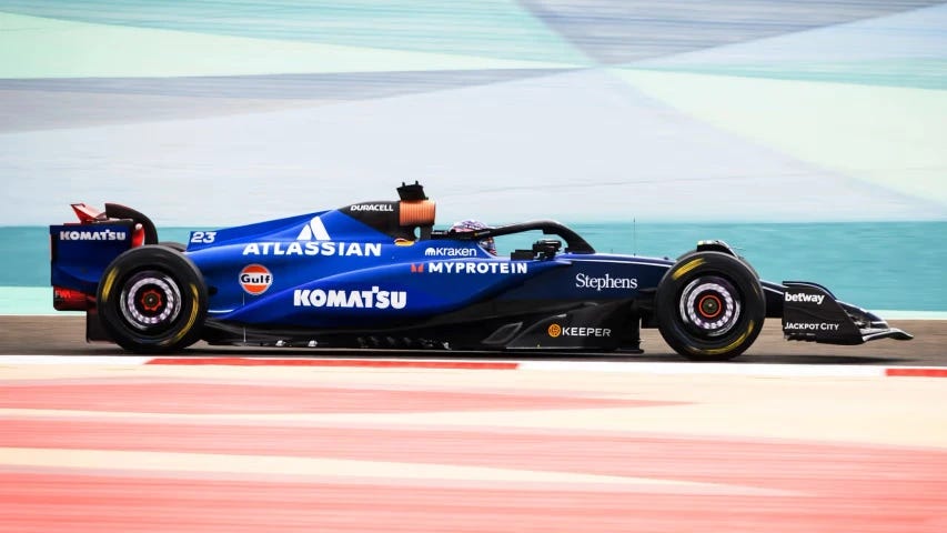 The 2025 Williams, driven by Alex Albon, during testing at Bahrain. The brakes are glowing. The perspective has sandwiched the car between two runoff areas with geometric patterns. Above is blue and red below. The 2025 Williams, driven by Alex Albon, during testing at Bahrain. The brakes are glowing. The perspective has sandwiched the car between two runoff areas with geometric patterns. Above is blue and red below.