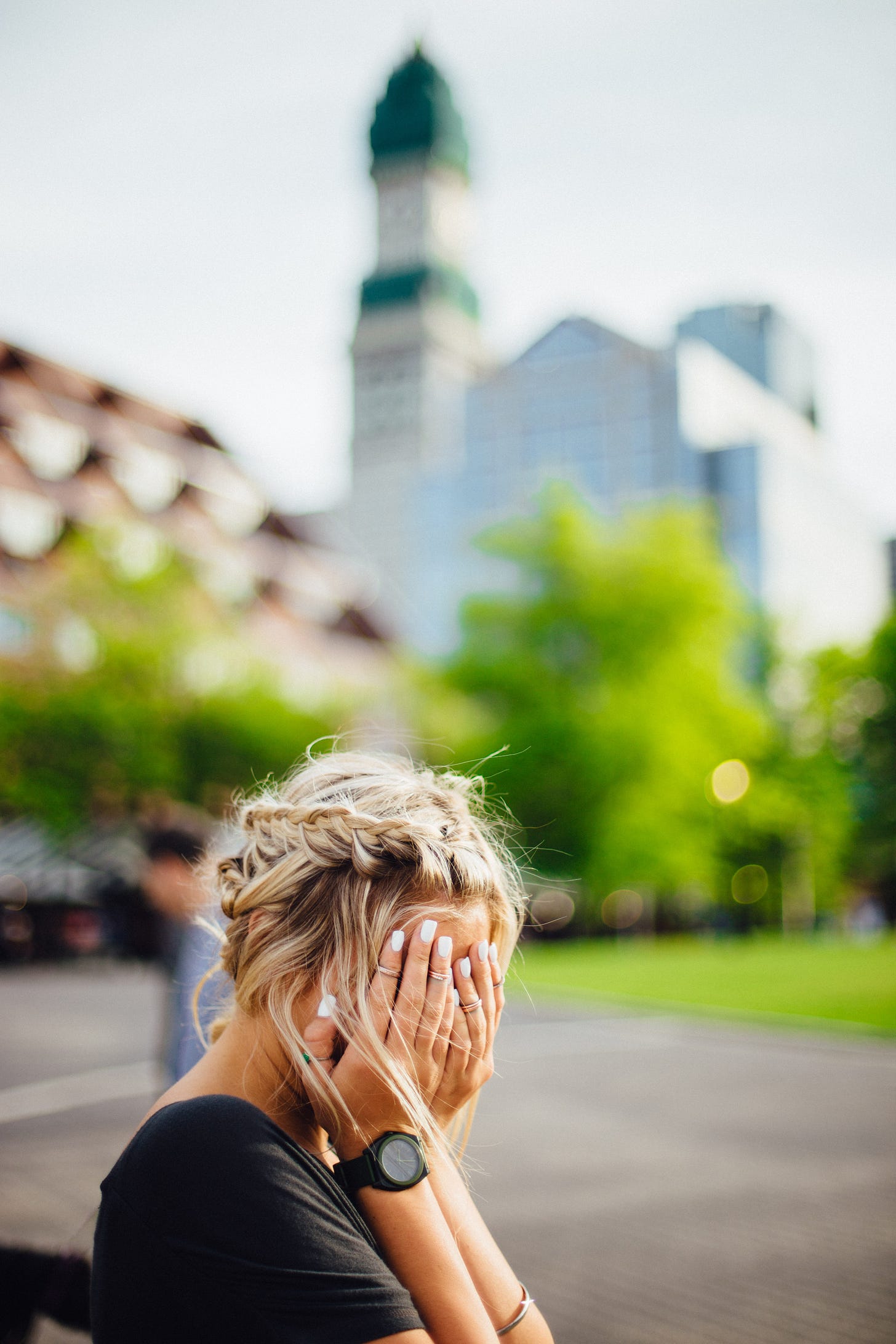 Blond woman sits with her hands covering her face. Photo by Abigail Keenan via Unsplash