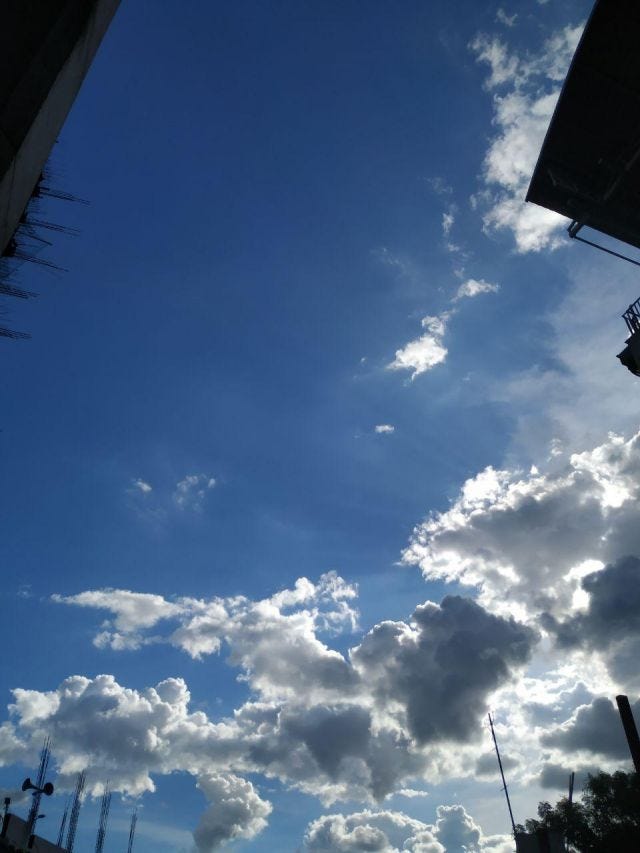 A shot of white clouds with silver outlines in a blue sky.