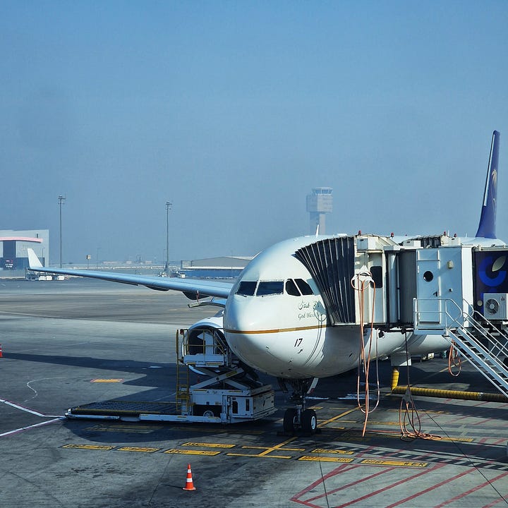 On the left, the Saudia Airbus A330-300, registered HZ-AQ17, ready to receive passengers for flight SV310 to Riyadh. On the right, view over Riyadh with focus on the Kingdom Centre, the city’s most iconic building.