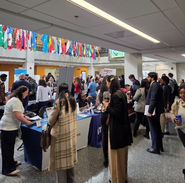 Students and employers on lower level of Galleria at tables, conversing and exchanging documents