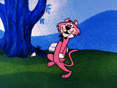 L'antropomorfo leone rosa Snagglepuss, con la sua tipica camicia bianca e farfallino nero, avanza con un passo saltellante e un sorriso sul viso, su un prato verde con un grande albero blu e montagne azzurre sullo sfondo.