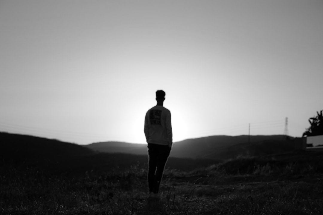 man in blue shirt standing on brown field during sunset man in blue shirt standing on brown field during sunset