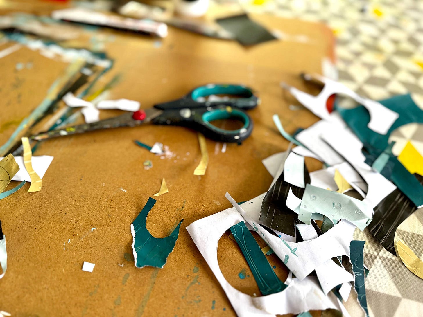 Drawing board with cut scraps of collage papers and a pair of scissors