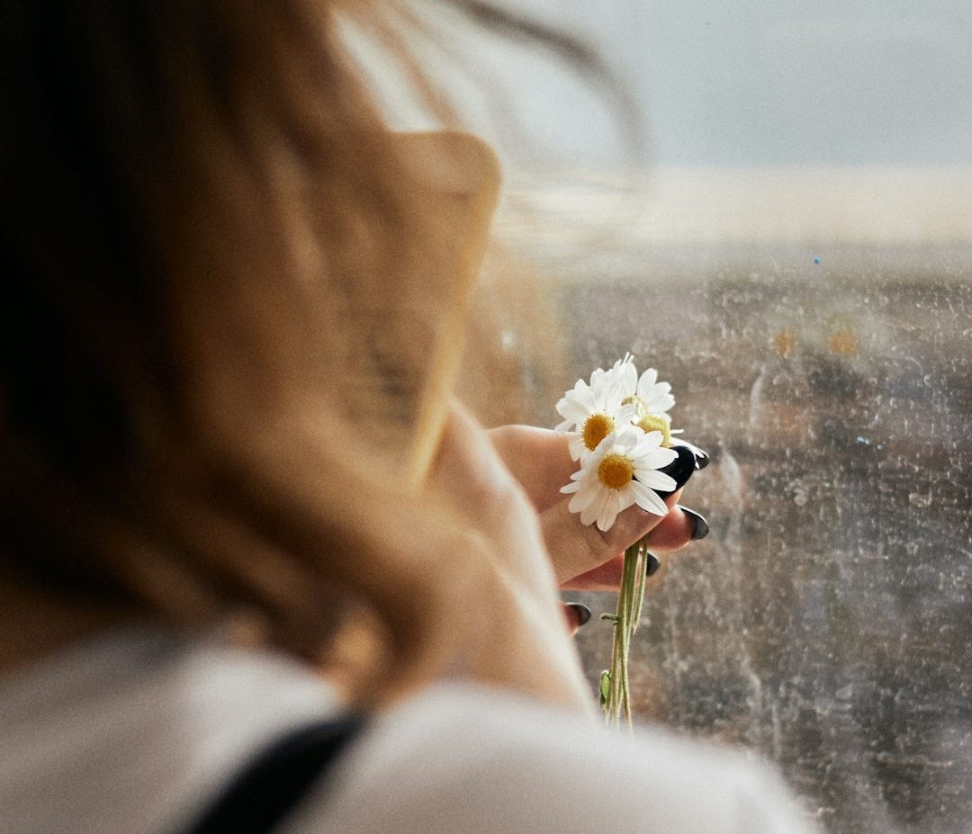 woman in white long sleeve shirt holding white flower