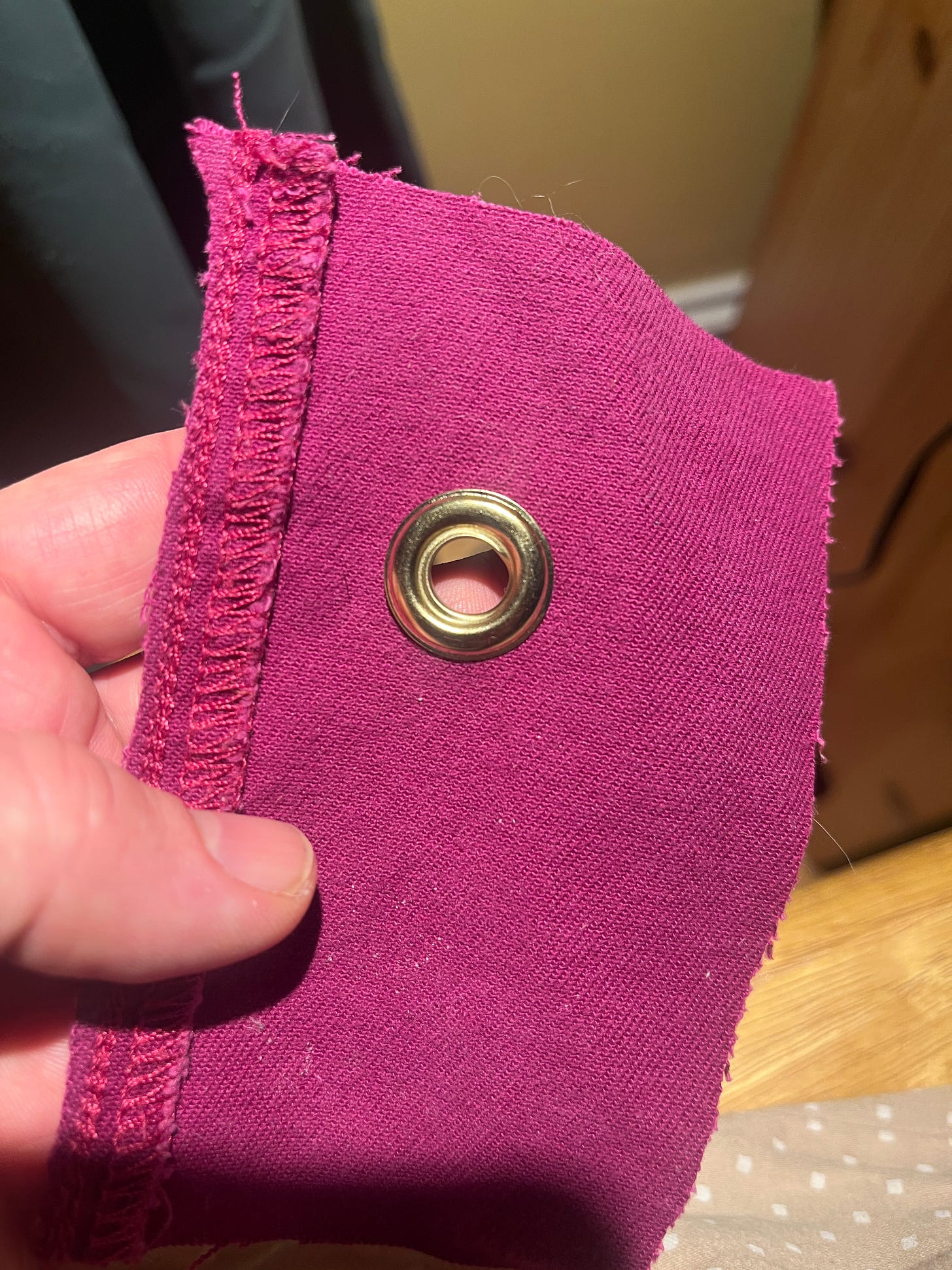 A round brass grommet in a scrap of pink-ish fabric.