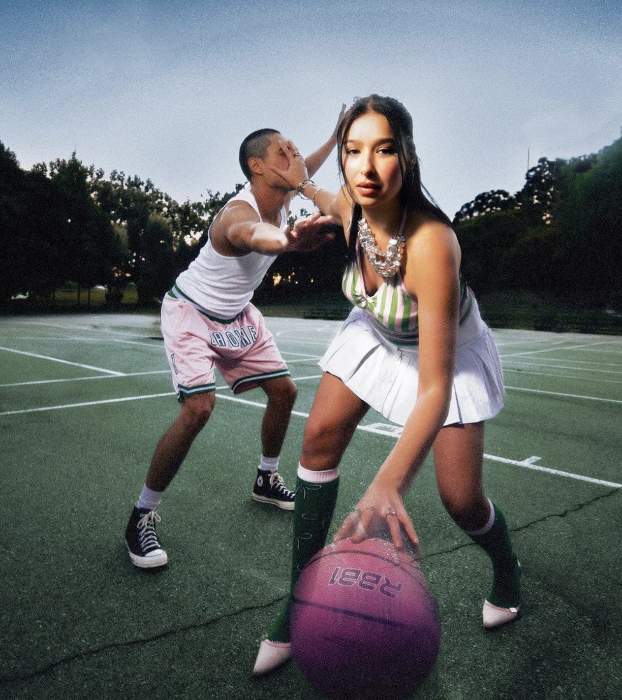 Woman in a pleated skirt and knee socks dribbling a basketball on an outdoor court Woman in a pleated skirt and knee socks dribbling a basketball on an outdoor court