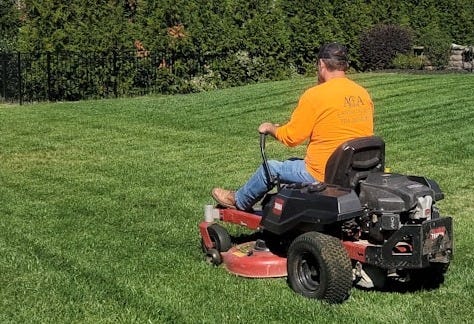 A man riding on the back of a lawn mower A man riding on the back of a lawn mower