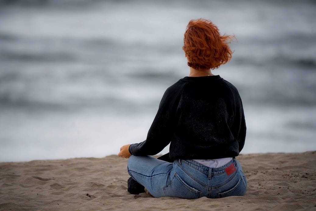 a woman sitting in the sand on the beach