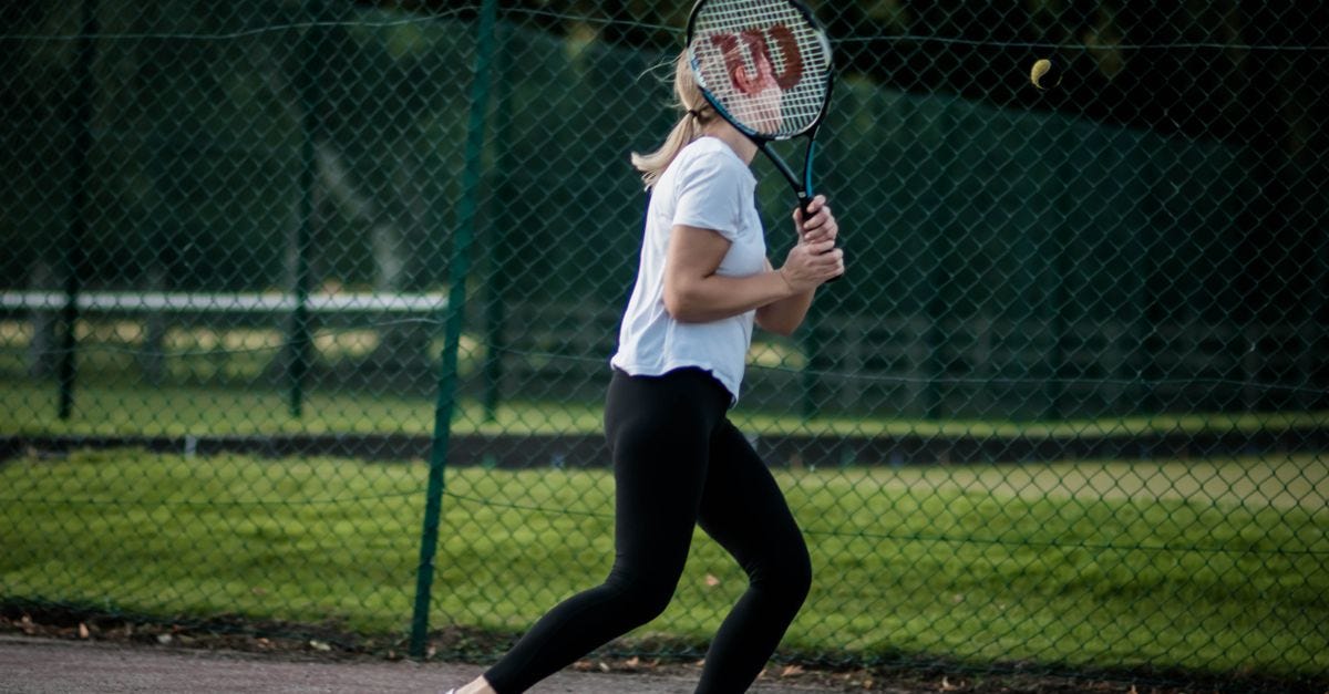 Photo: Zenith / Pexels A woman playing tennis outdoors, poised with her racket for a return shot on a sunny day.