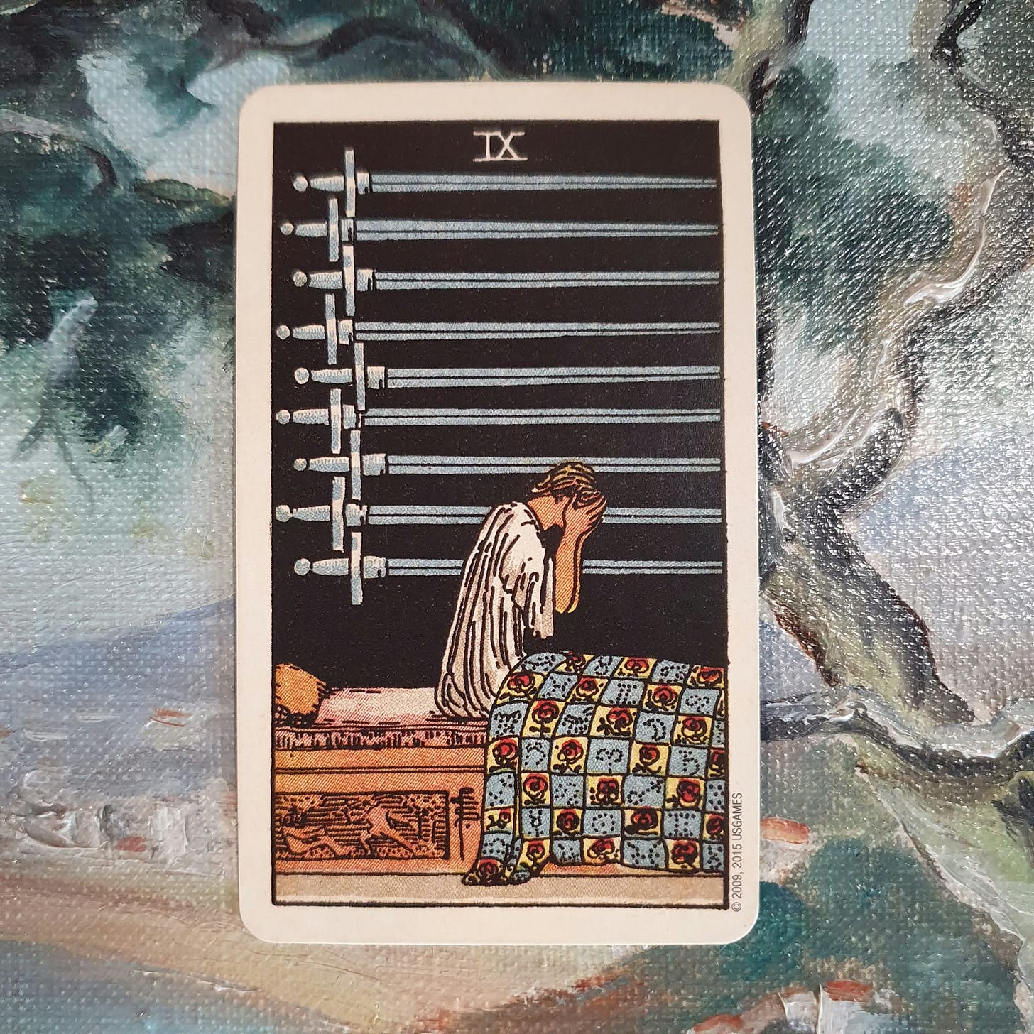 Nine of Swords tarot card showing a distressed figure sitting up in bed with their face in their hands beneath nine horizontal swords. Nine of Swords tarot card showing a distressed figure sitting up in bed with their face in their hands beneath nine horizontal swords.