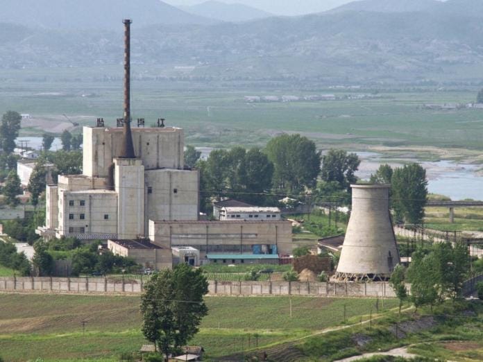 A factory with a chimney and a factory in the background

Description automatically generated
