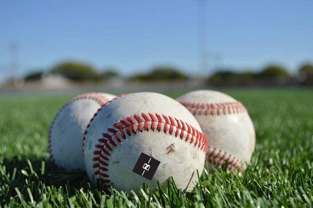 white and red baseball on green grass during daytime