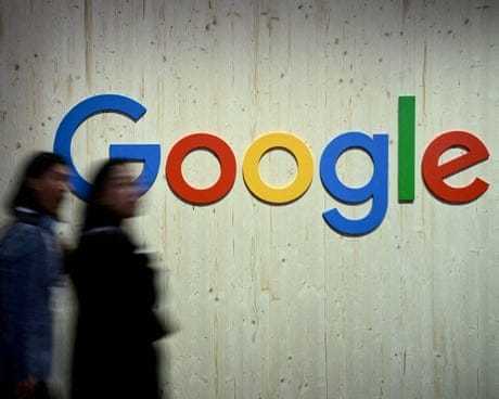 People walk next to a Google logo