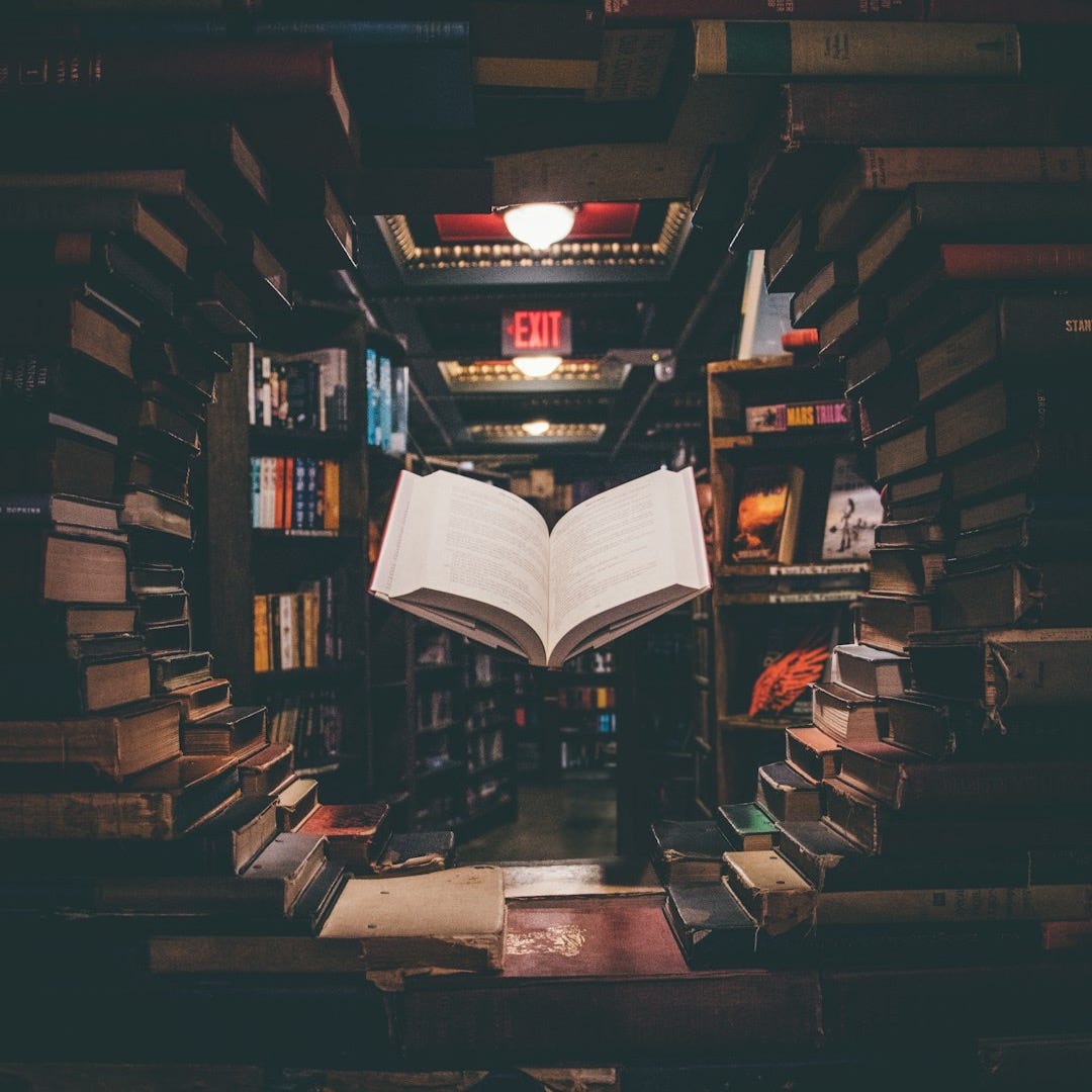 view of floating open book from stacked books in library view of floating open book from stacked books in library