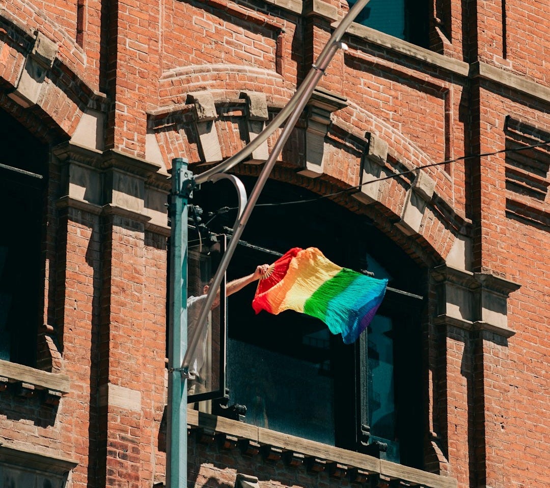 a rainbow flag is flying in front of a building a rainbow flag is flying in front of a building