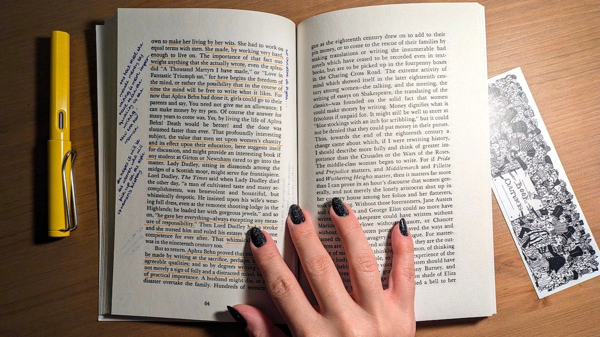 Overhead view of a book open, with annotations in the margins and a hand holding it open.