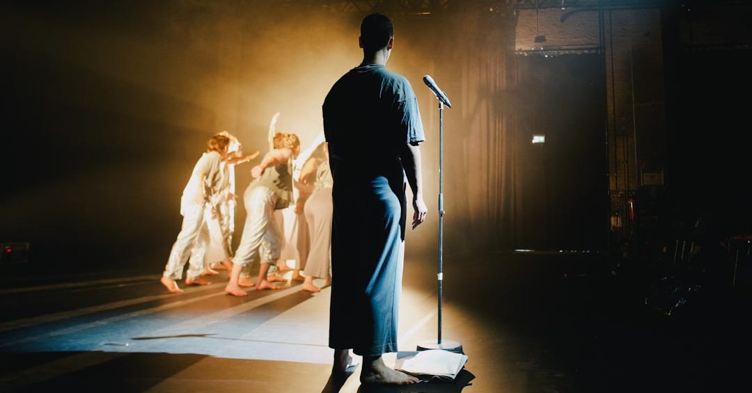 a man standing in front of a microphone on a stage a man standing in front of a microphone on a stage