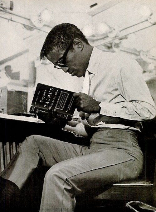 This may contain: a man sitting in a chair reading a book