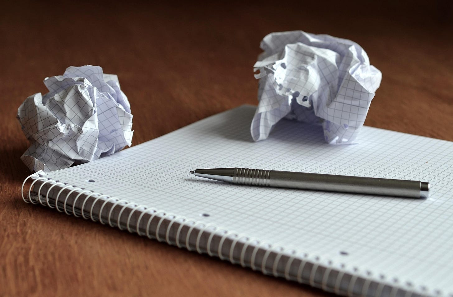 A notepad and pen with two scrunched up balls of paper