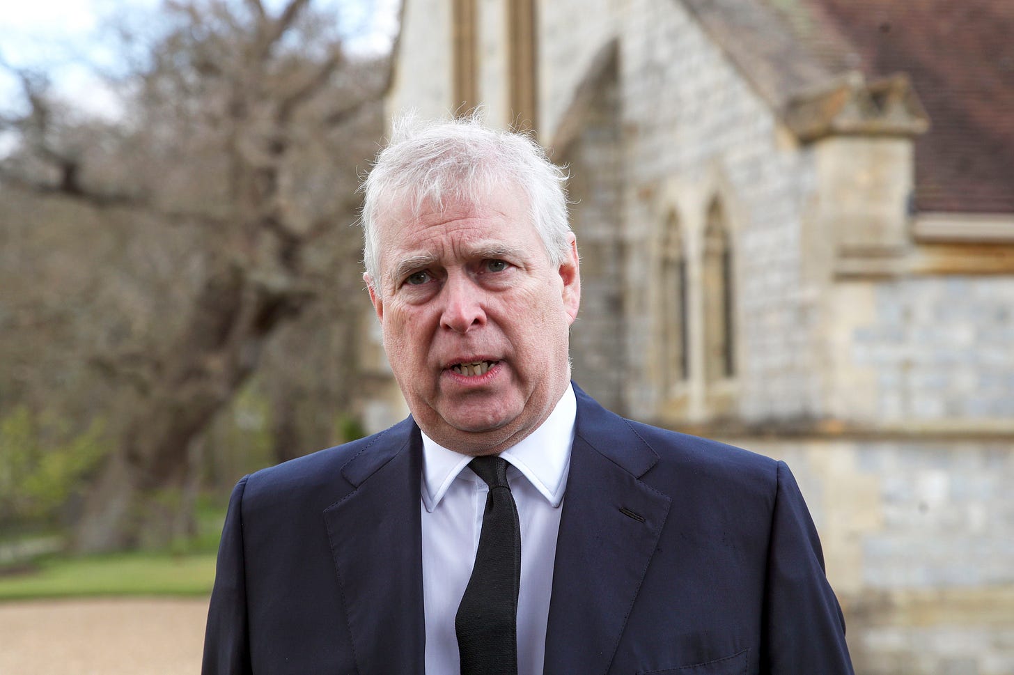 Prince Andrew in a dark suit and white shirt outside a church