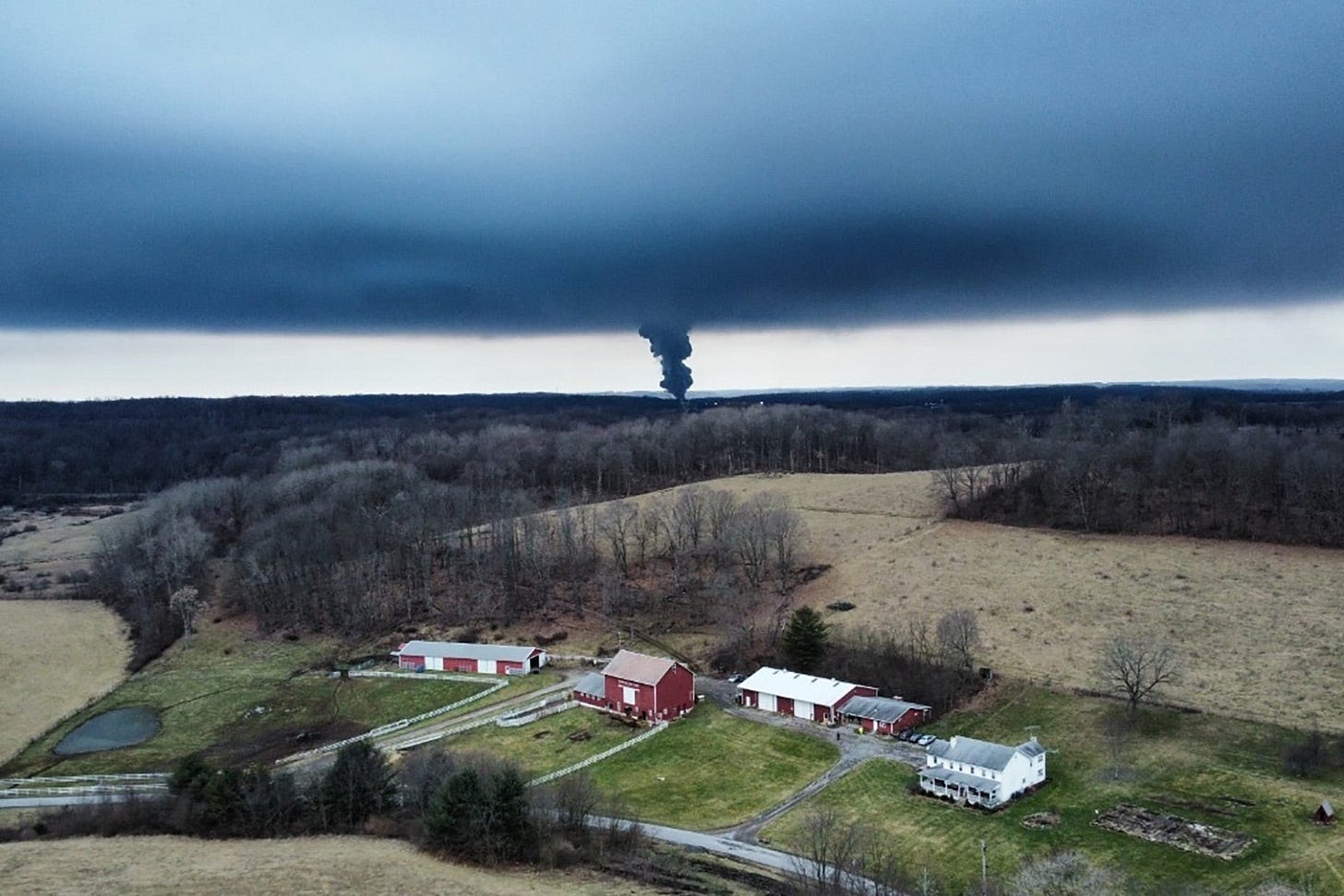 A thick plume of black smoke seen from a distance over farmland. A thick plume of black smoke seen from a distance over farmland.