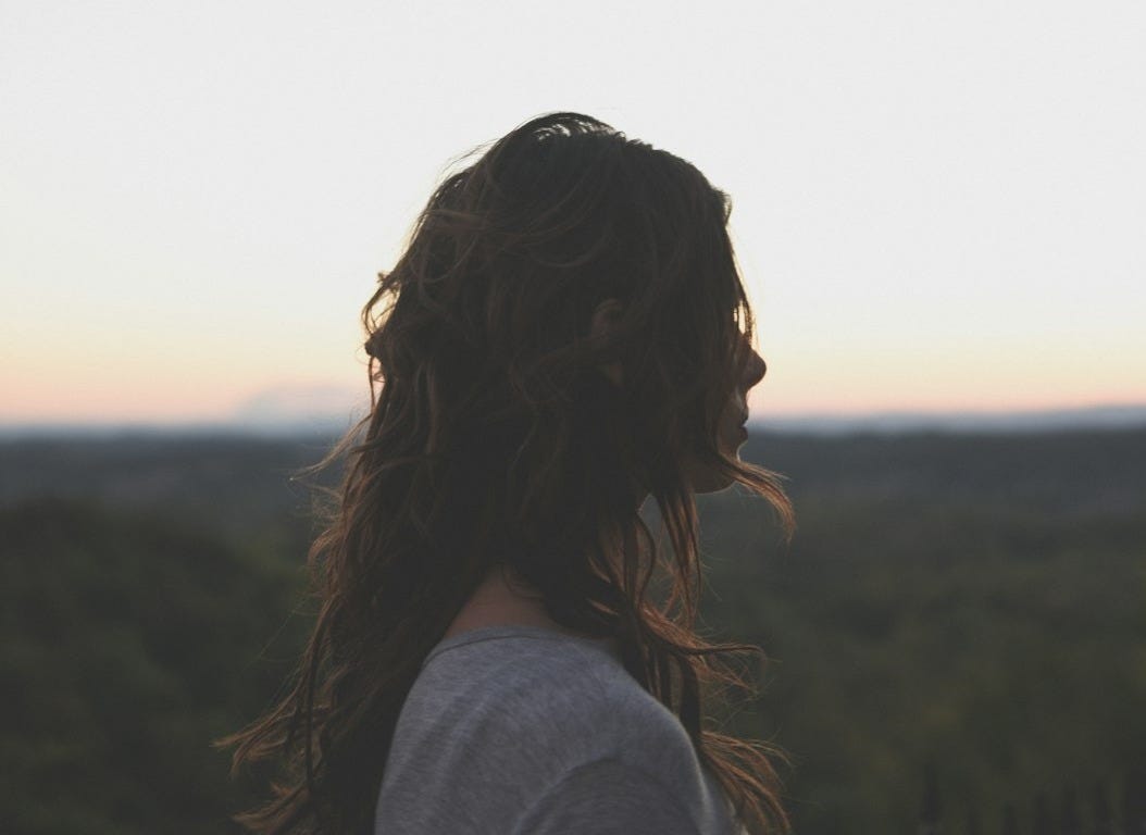 brunette hair woman wearing gray top looking side way