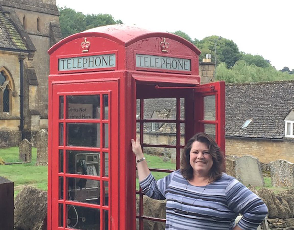Melinda Pajak, standing next to a red phone booth in England