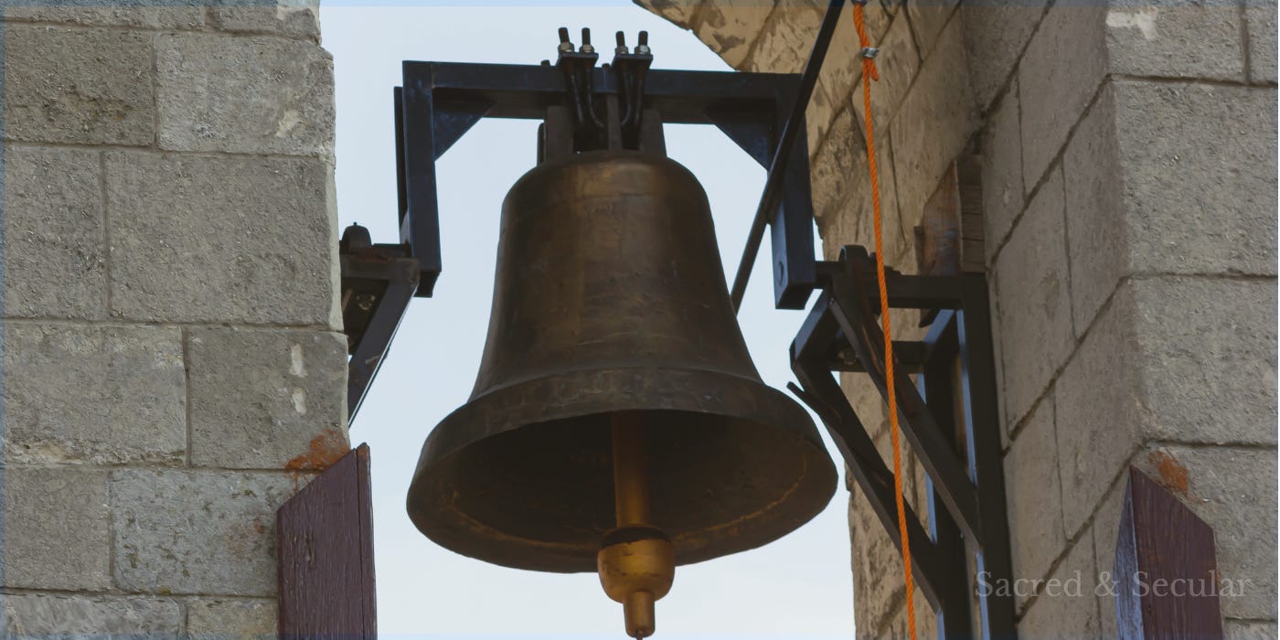 A large bronze church bell hanging in a stone bell tower, overlooking the surrounding village. A large bronze church bell hanging in a stone bell tower, overlooking the surrounding village.