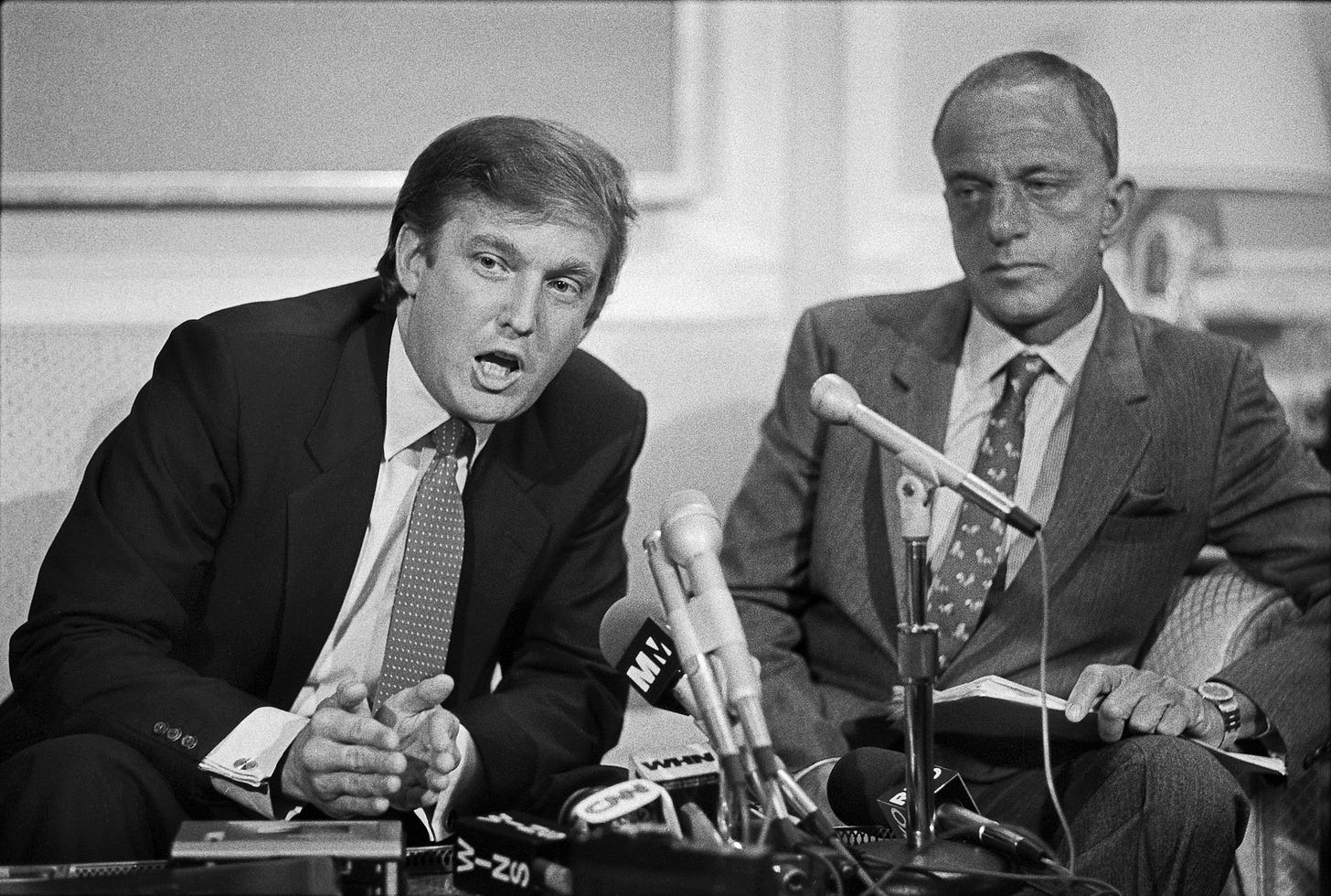 Donald Trump and Roy Cohn sitting side by side behind microphones at a press conference in October 1984 Donald Trump and Roy Cohn sitting side by side behind microphones at a press conference in October 1984