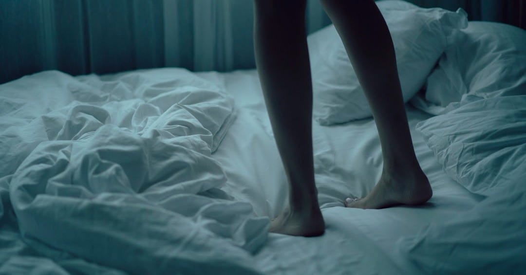 person standing on white bed
