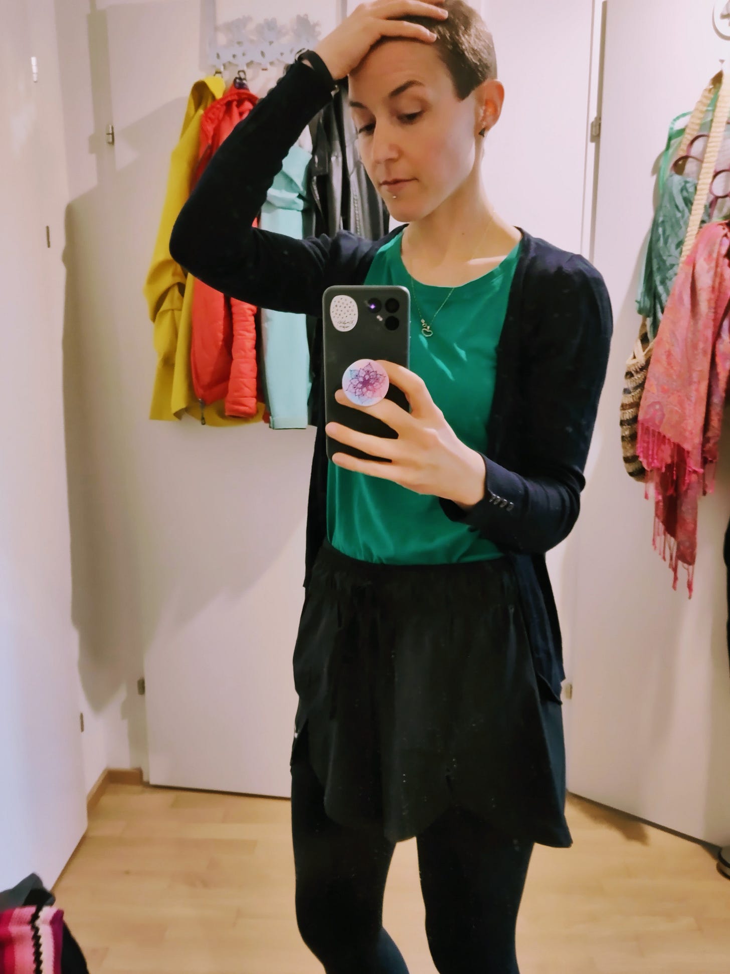 A white woman is standing in front of a mirror and takes a picture of herself. In one hand, she holds her phone, the other hand is on her head to draw attention to her short, brown her. She just got a buzzcut to make showering with Long Covid a little bit easier. A white woman is standing in front of a mirror and takes a picture of herself. In one hand, she holds her phone, the other hand is on her head to draw attention to her short, brown her. She just got a buzzcut to make showering with Long Covid a little bit easier.