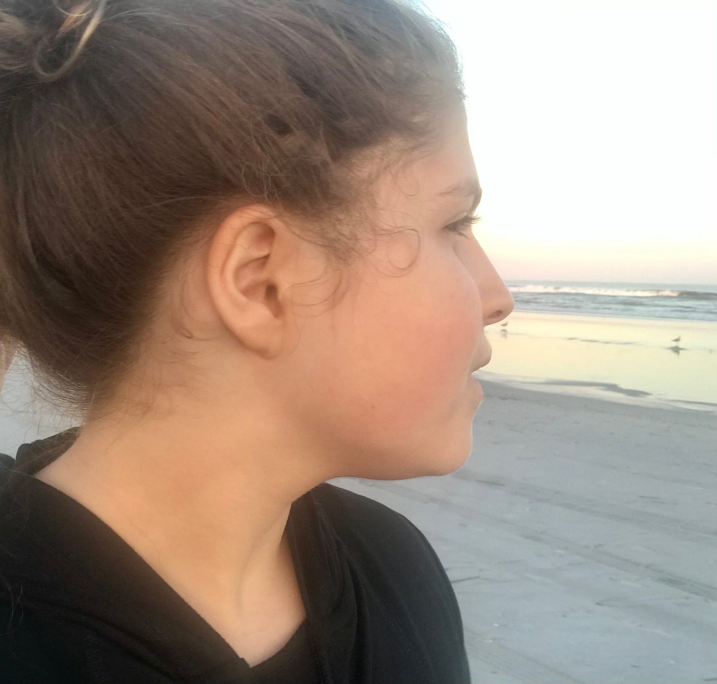 The poet Amelia Bell looks out over the ocean and her ear is turned toward the viewer.